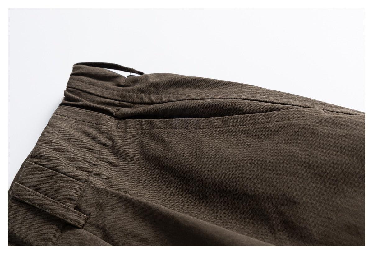 Close-up of brown trousers showing a rear welt pocket, belt loop, and waistband seam.