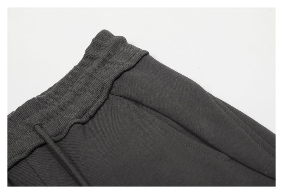 Close-up of charcoal pants showing the ribbed waistband and curved front pocket opening.