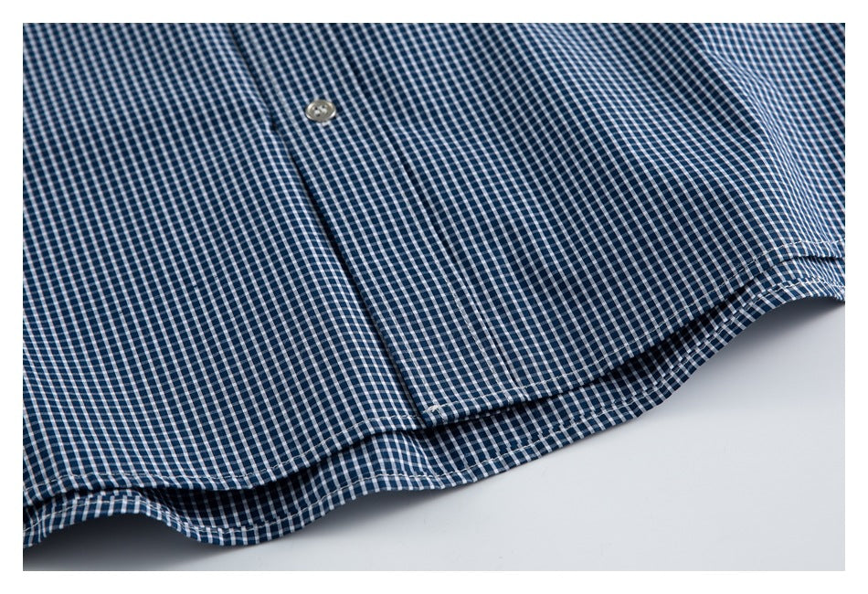 Close-up of the lower front of a navy-and-white gingham shirt, showing a pocket edge and hem.