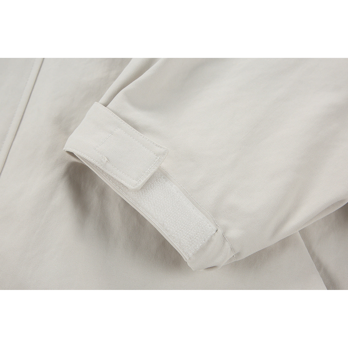 Close-up of an ivory jacket cuff with an adjustable hook-and-loop tab.
