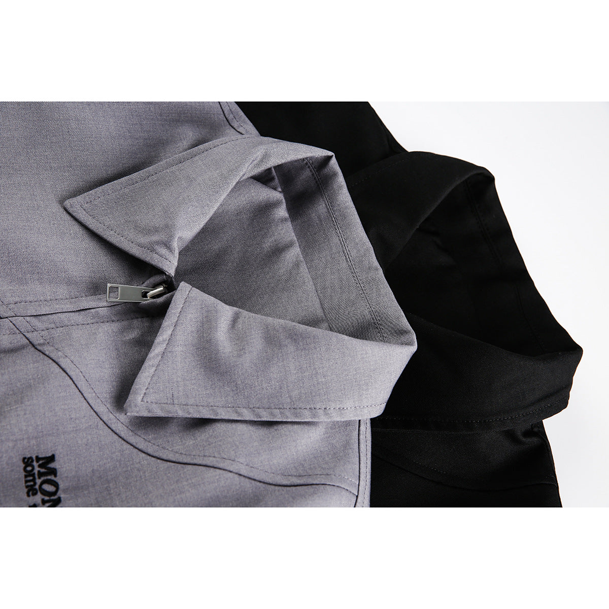 Close-up of overlapping gray and black jacket collars with a zipper on the gray jacket.