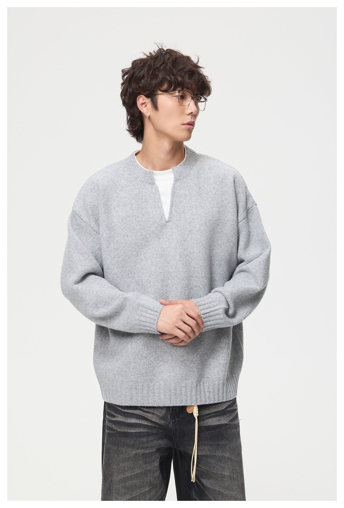 Model wearing a light gray oversized split-neck sweater with ribbed cuffs and hem, shown from the front.