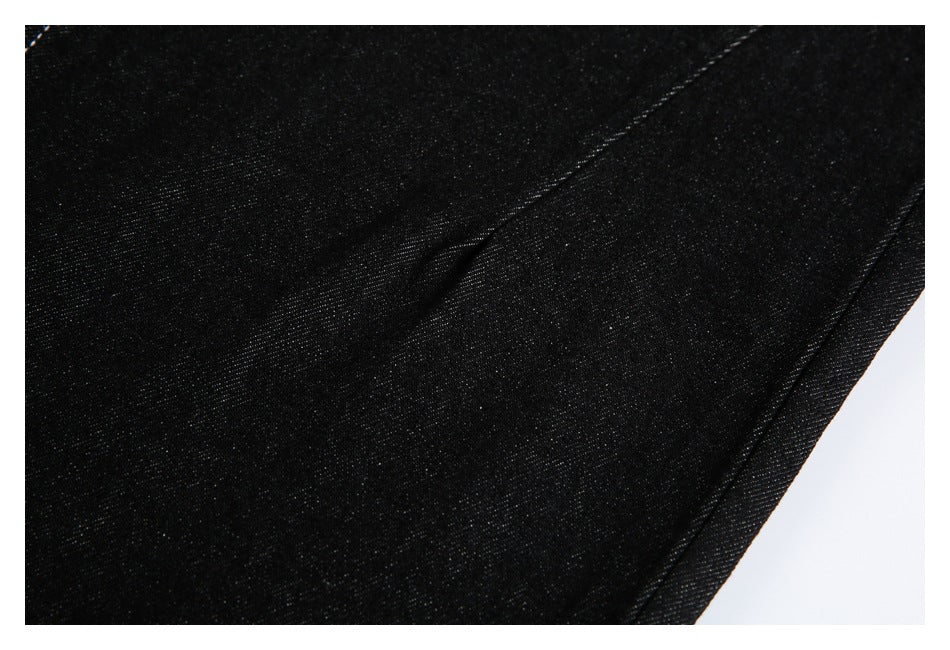 Close-up of black denim showing its surface and a diagonal stitched seam.