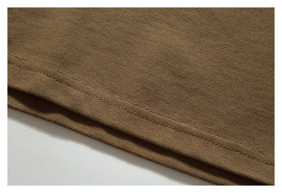 Close-up of brown textured polo fabric folded to show a stitched edge.
