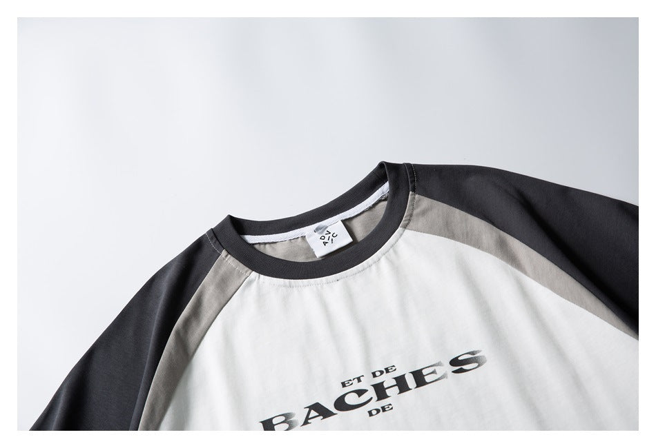 Close-up of a white raglan T-shirt with charcoal sleeves, gray shoulder panels, and black French lettering.