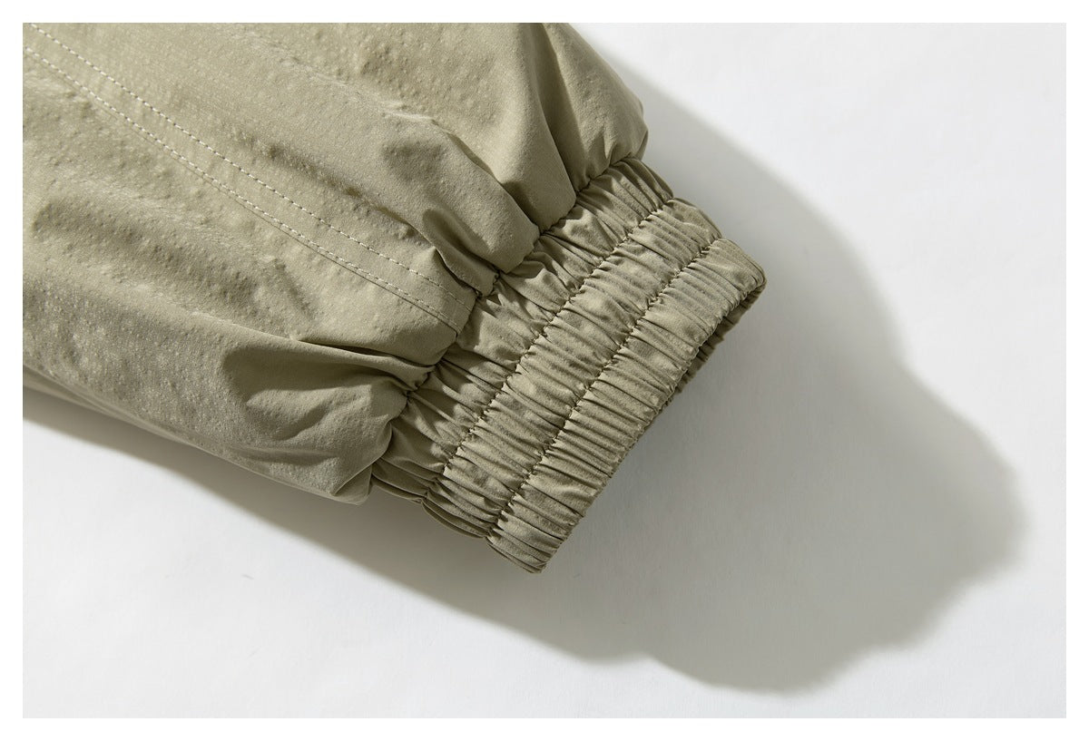 Close-up of an olive-khaki jacket sleeve with a wide gathered elastic cuff.