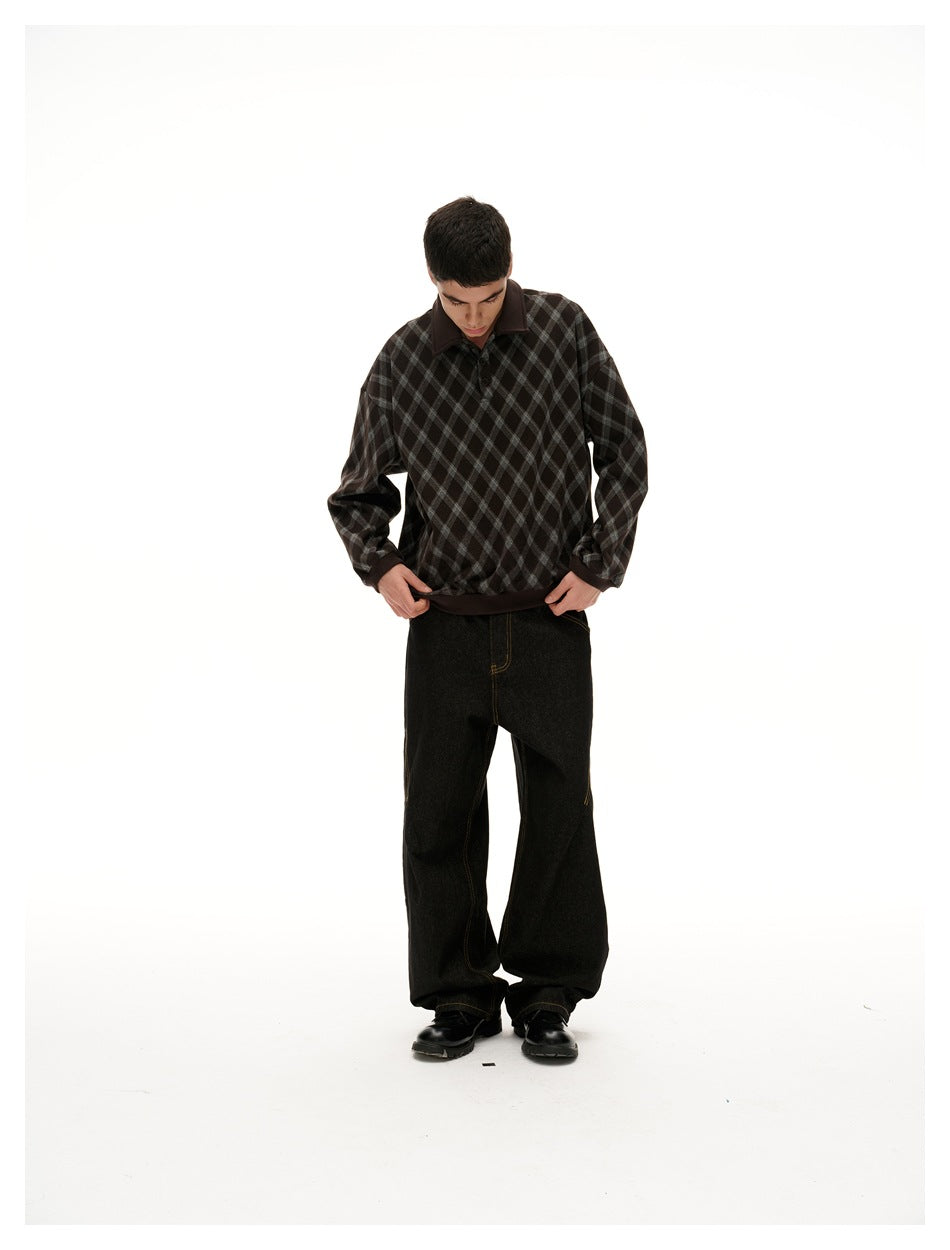 Model looking down and holding the hem of a dark brown and gray diamond-check pullover, paired with black wide-leg pants.