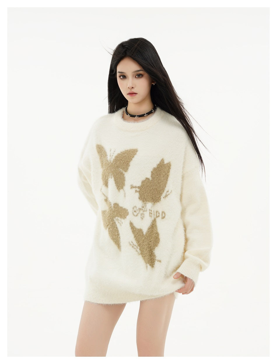 Model wearing an oversized ivory crewneck sweater with tan butterfly motifs and ribbed cuffs and hem, front view.