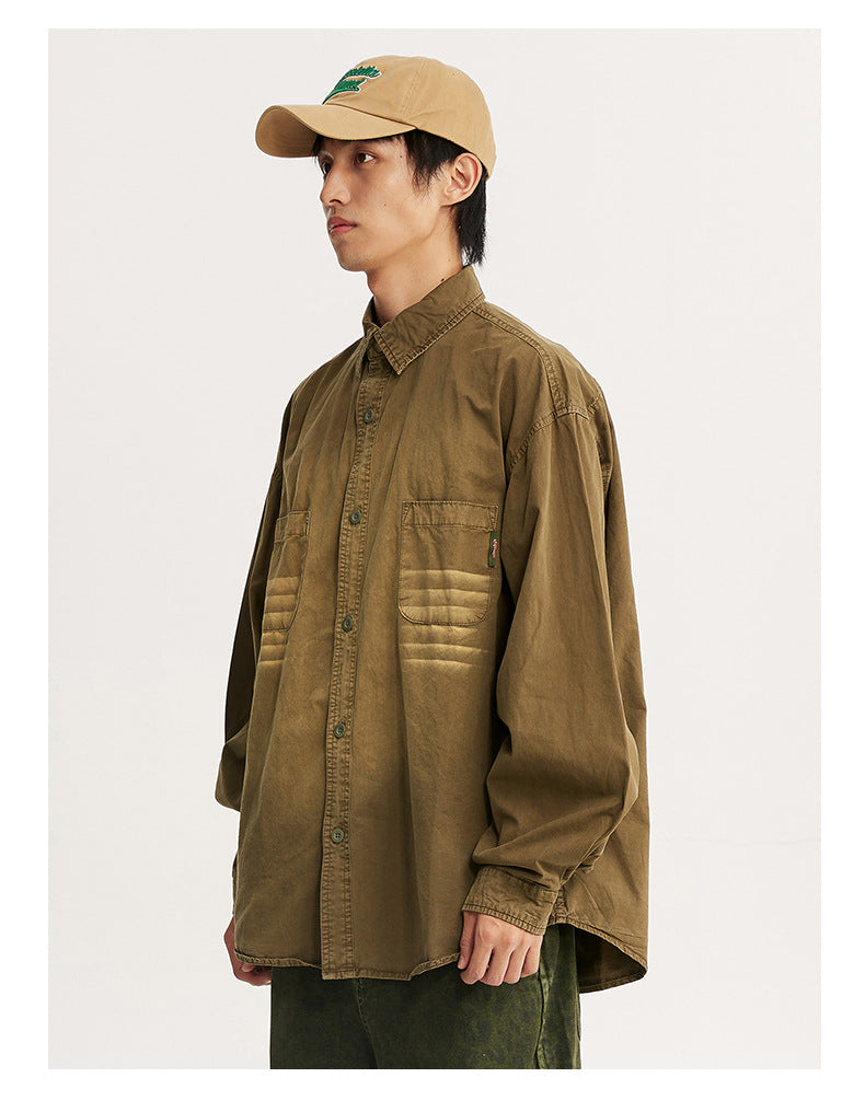 Side view of a model wearing an oversized brown shirt with two chest pockets and faded horizontal bands.