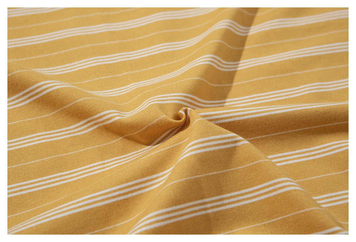 Close-up of mustard yellow T-shirt fabric gathered to show its thin white horizontal stripes.