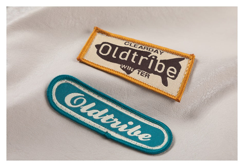 Close-up of two embroidered brand patches on light beige jacket fabric.