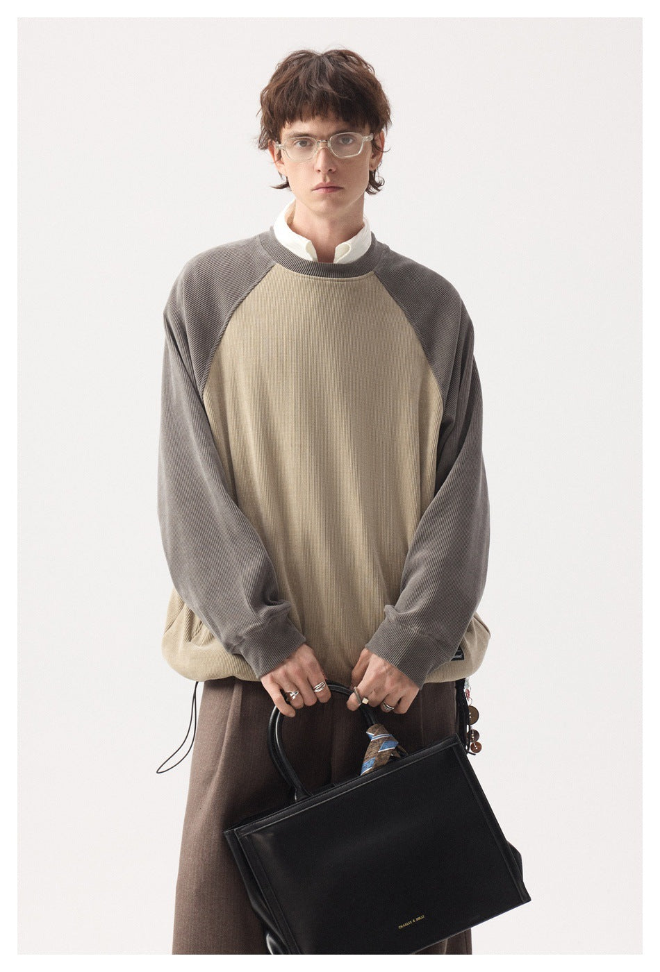 Front view of a model wearing a beige pullover with gray raglan sleeves and a ribbed crew neck.