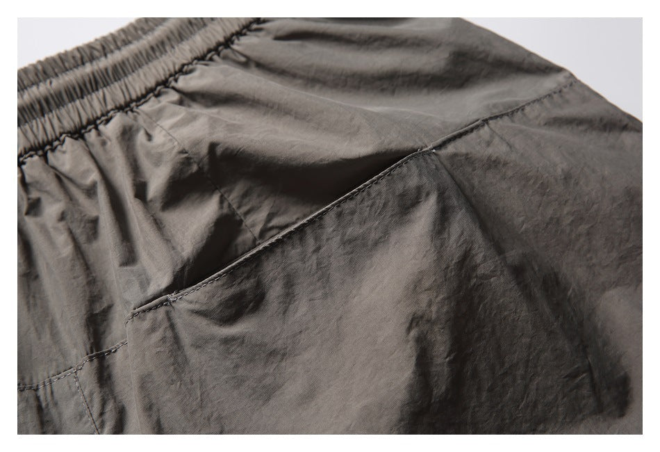 Close-up of a stitched pocket panel and gathered waistband on charcoal-gray shorts.