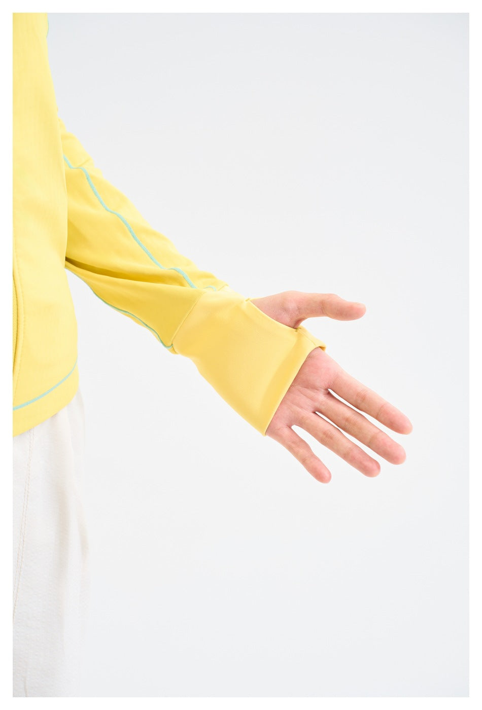 Close-up of a yellow jacket sleeve with turquoise seam trim and an extended thumbhole cuff.