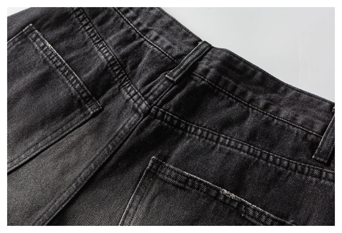Close-up of black jeans showing the waistband, belt loops, seams, and back pocket edges.