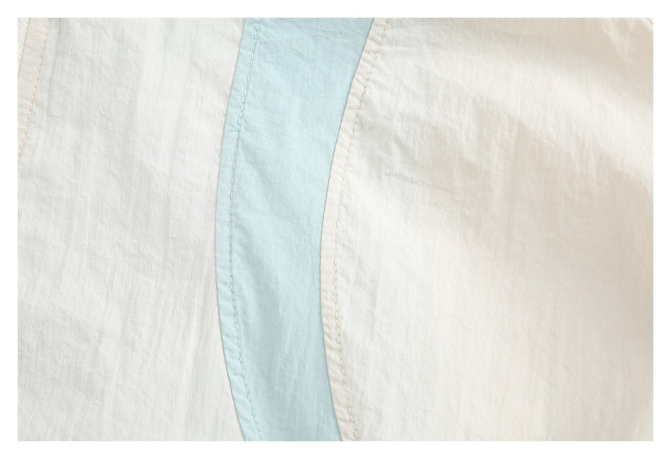Close-up of a pale blue contrast strip sewn between cream panels on the jacket.
