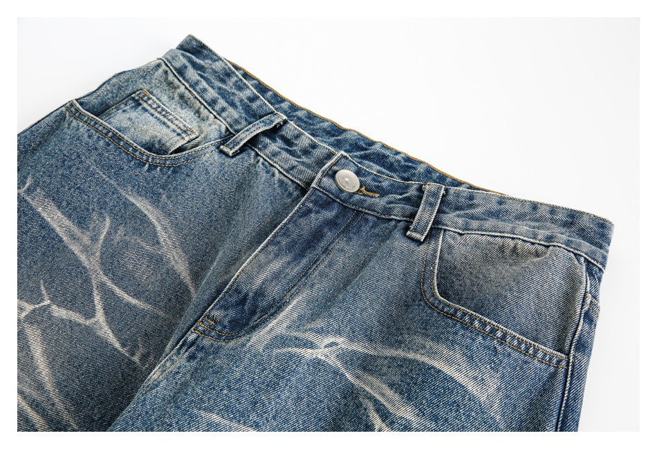 Close-up of the front waistband and pockets of blue jeans with pale branching faded patterns.