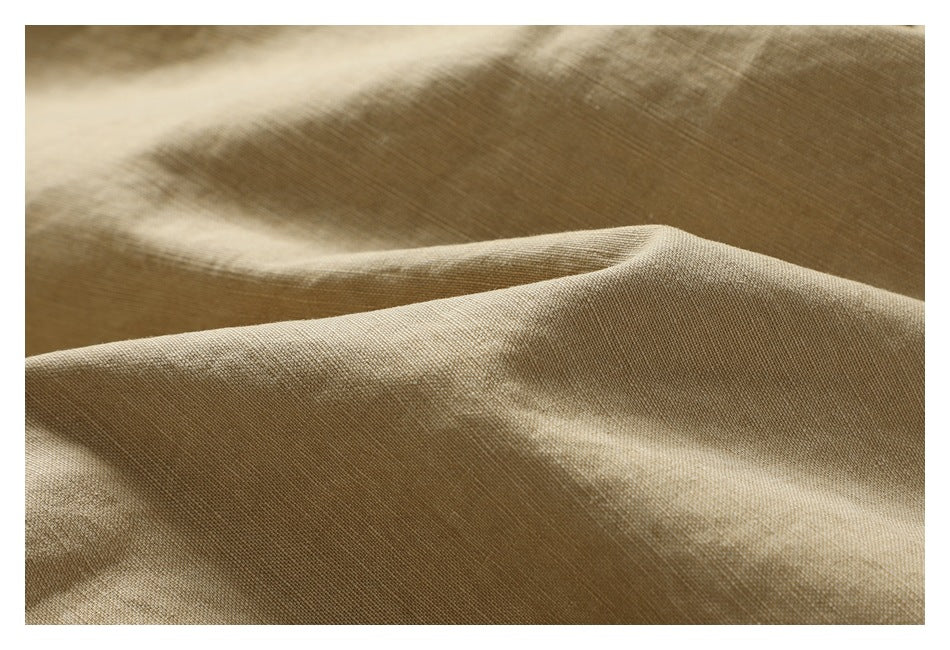 Close-up of tan garment fabric draped into soft folds, showing its subtle woven texture.