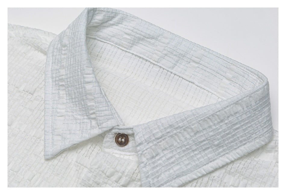 Close-up of a white textured shirt collar with a small brown button.