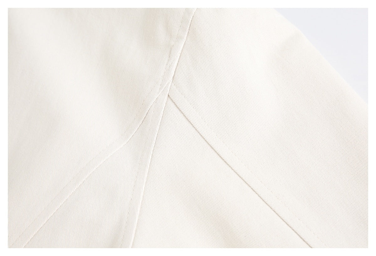 Close-up of ivory jacket fabric with curved seam lines and stitching.