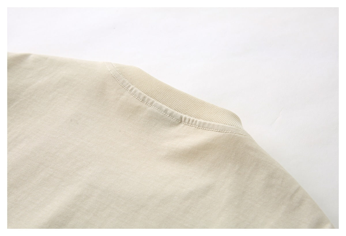 Close-up of the cream shirt's ribbed crew neckline and shoulder seam.
