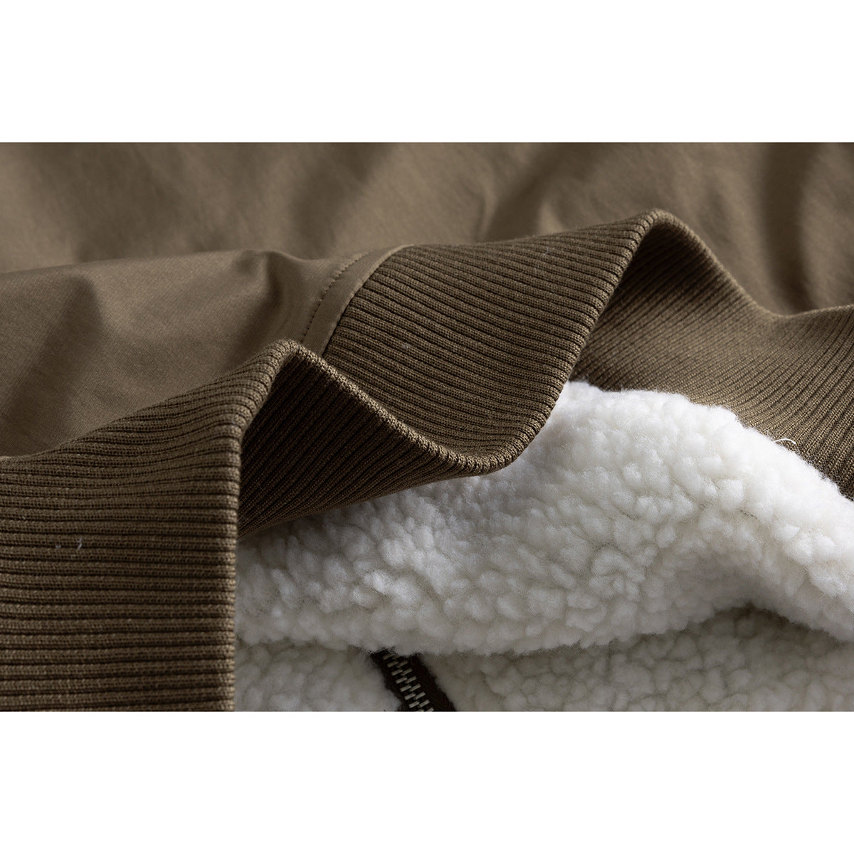 Close-up of a brown jacket's ribbed edge and plush white lining beside the zipper.