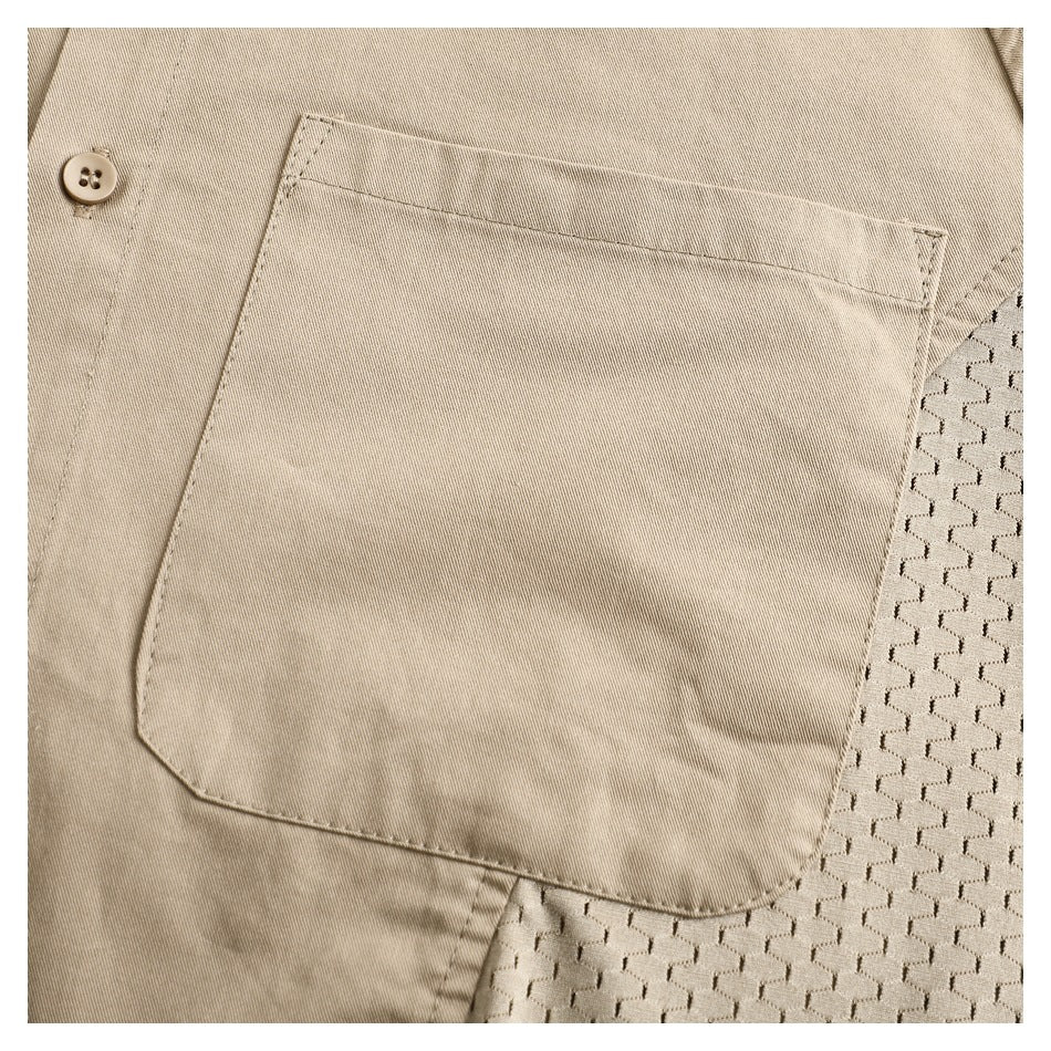 Close-up of a beige shirt with a large stitched chest pocket, a button, and a textured mesh side panel.