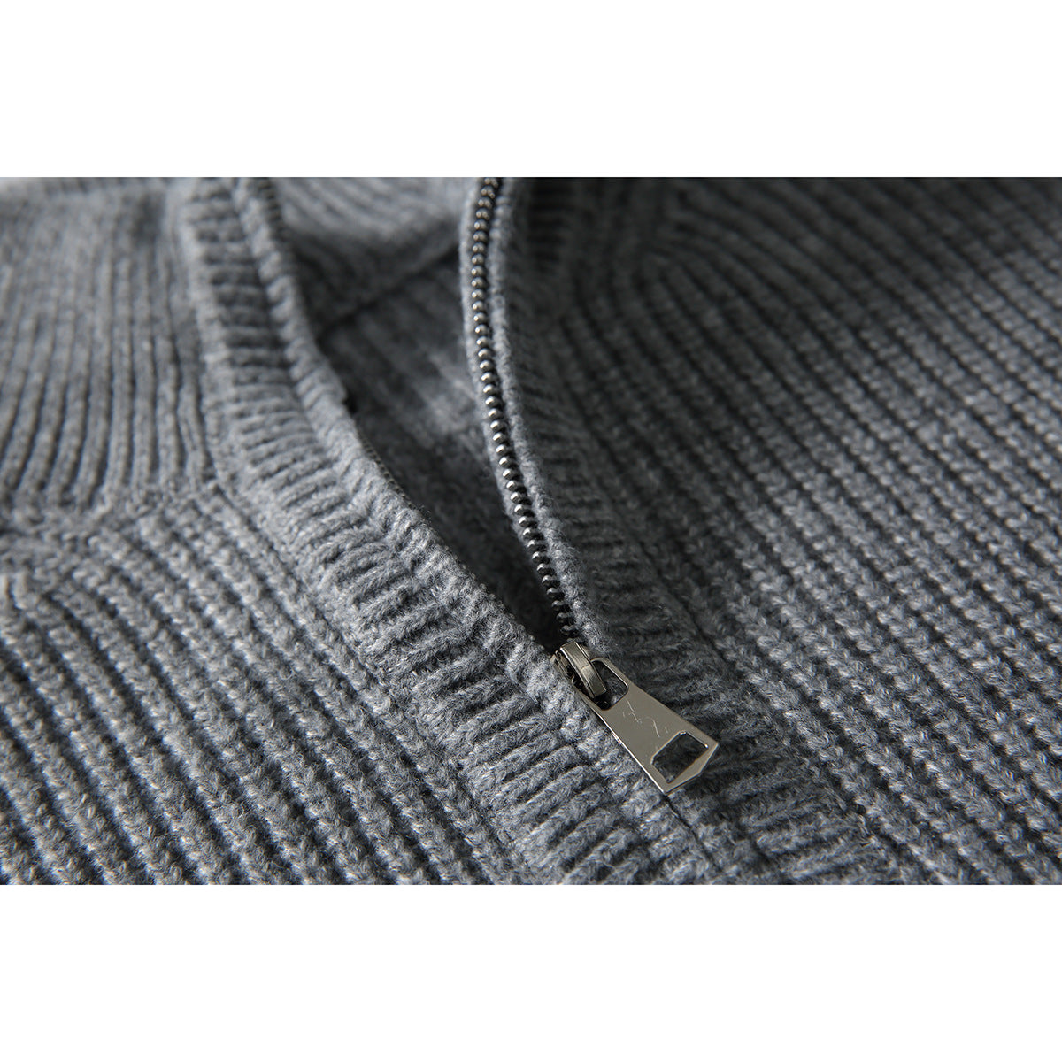 Close-up of a gray rib-knit sweater's quarter-zip collar and metal zipper pull.