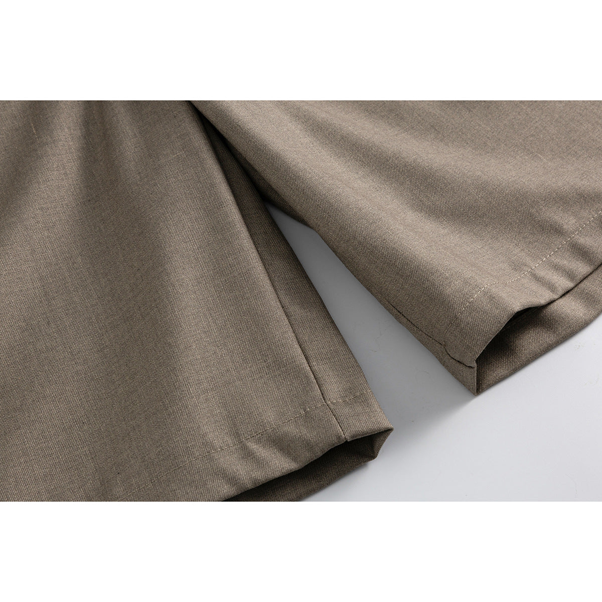 Close-up of taupe shorts showing the stitched hems and fabric at the leg openings.