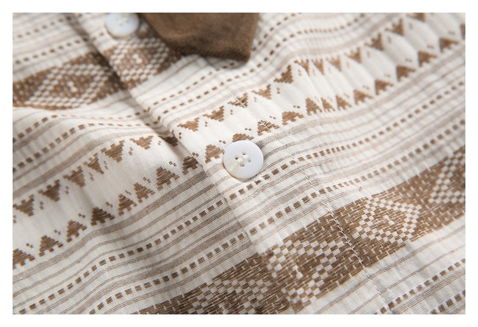 Close-up of a white button on cream fabric with brown geometric stripes and woven-looking motifs.
