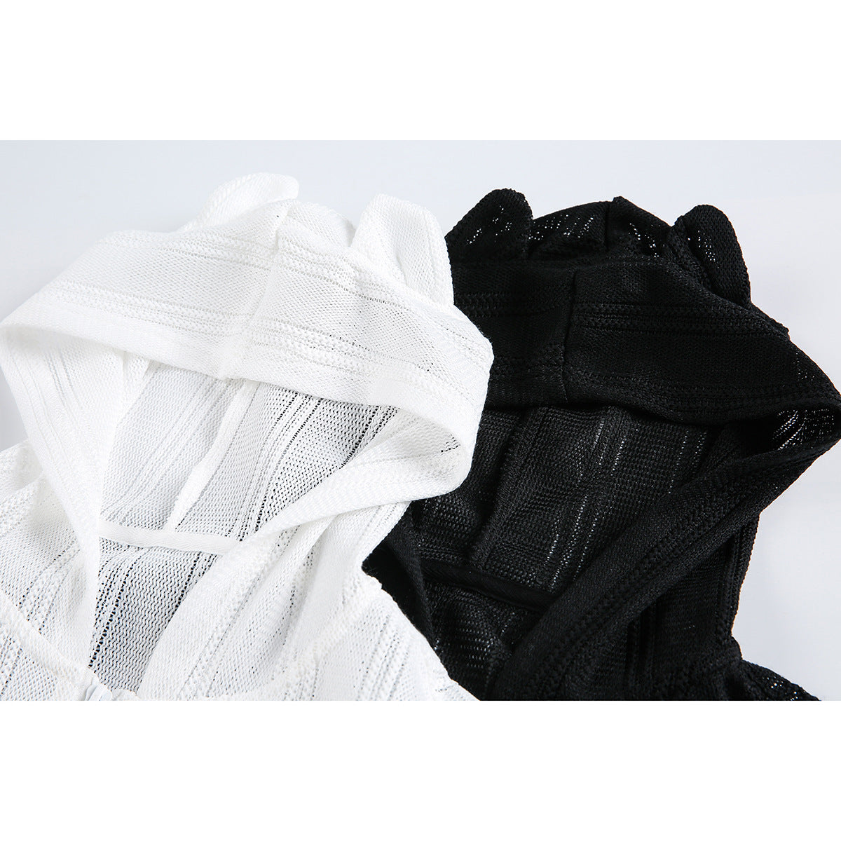 Close-up of white and black knit hoodies showing textured panels and raised hood details.