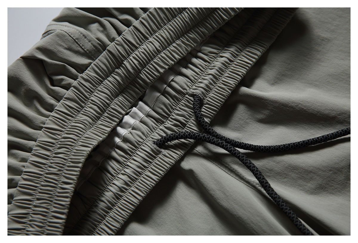 Close-up of gray pants with an elastic waistband and black braided drawcord.