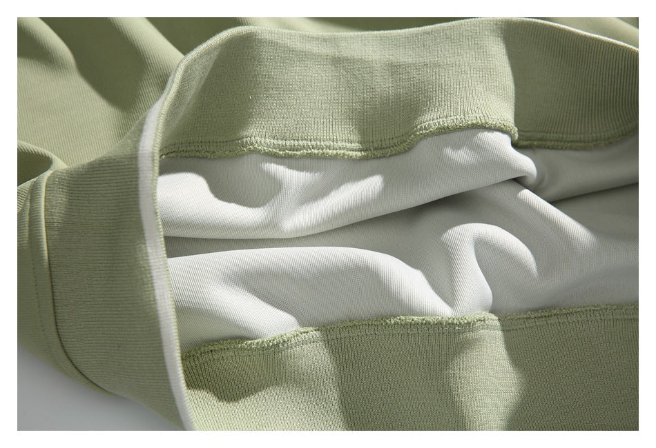 Close-up of pale sage-green garment edging and stitching around a white inner panel.