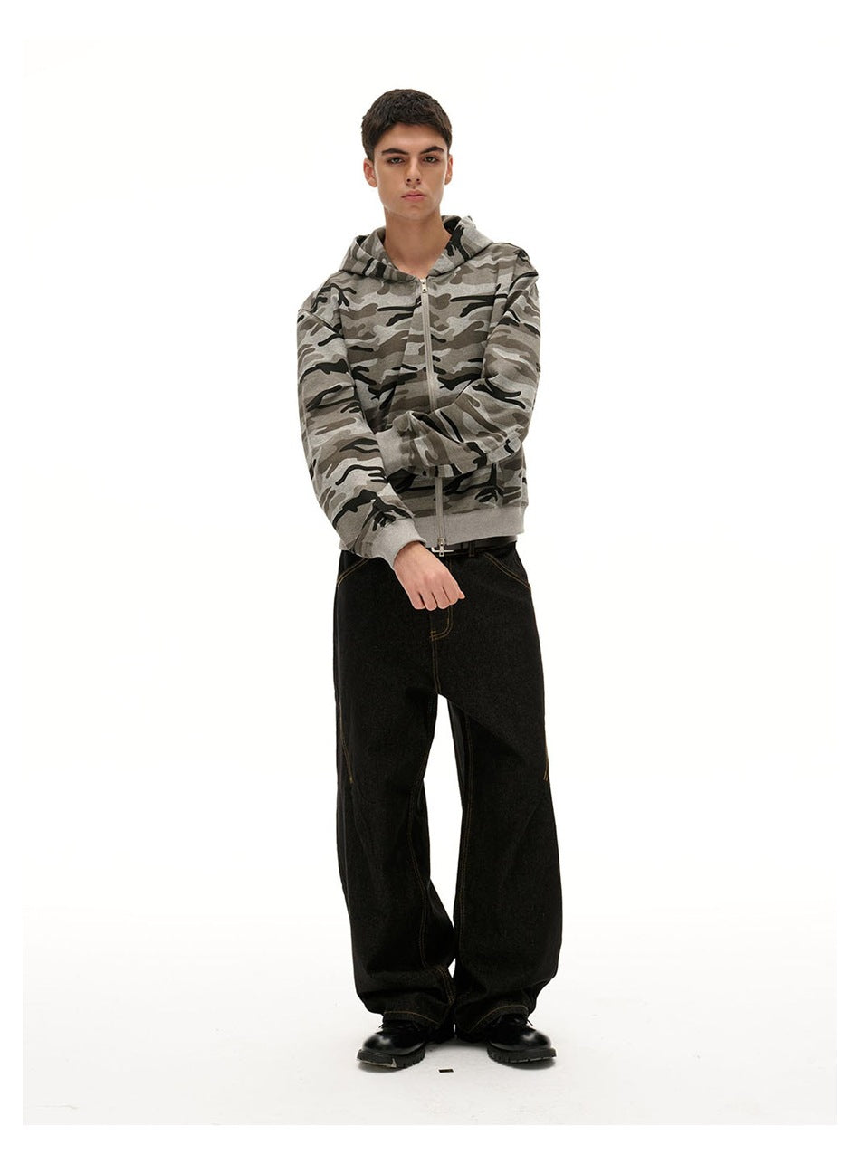 Model wearing black wide-leg jeans with a camouflage zip hoodie and black boots, standing front view