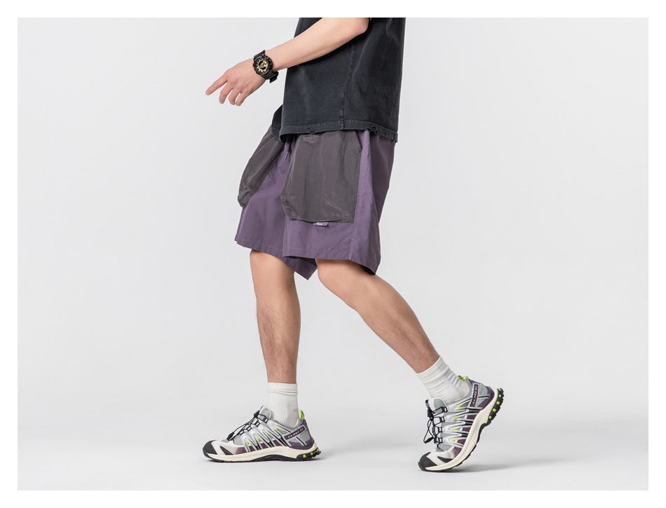 Side view of a model walking in muted purple shorts with large gray patch pockets.