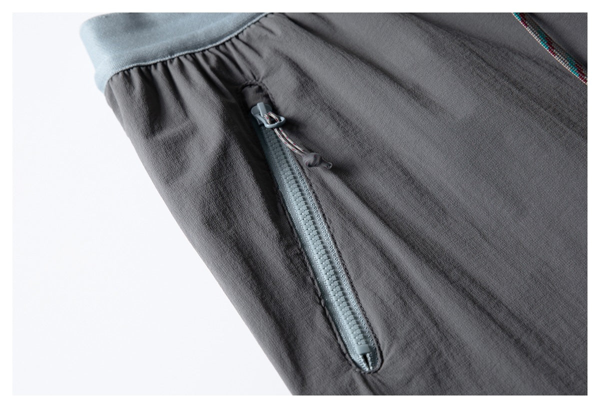 Close-up of a dark charcoal garment with a light gray-blue zipper pocket and matching trim.