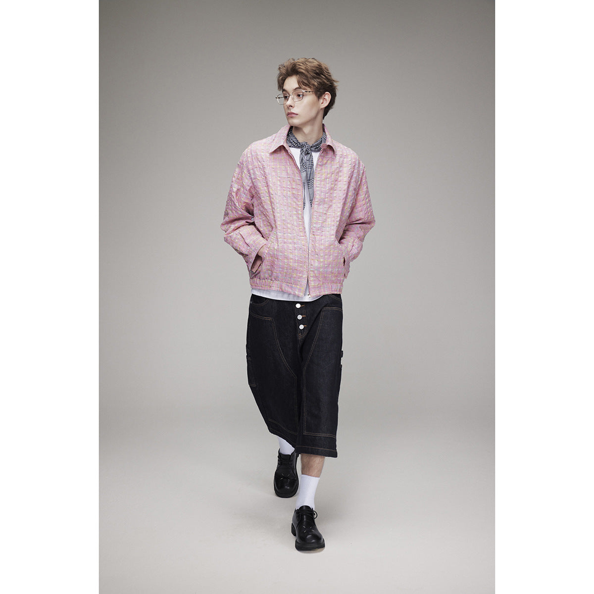 Model wearing a pink plaid zip-front jacket over a white shirt and dark denim shorts.