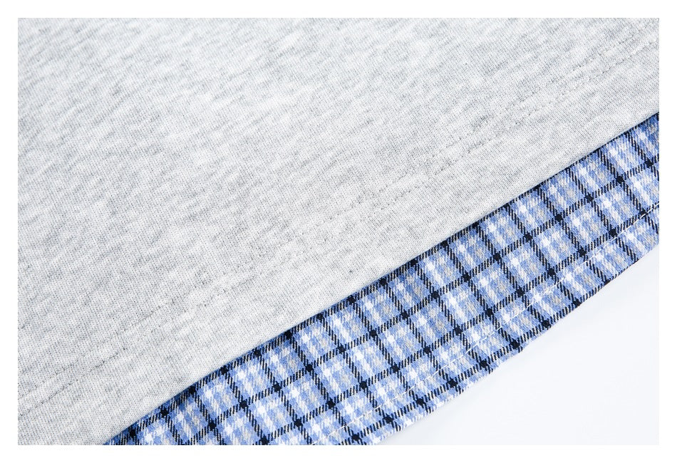 Close-up of a light gray knit hem with blue-and-black plaid fabric visible beneath it.