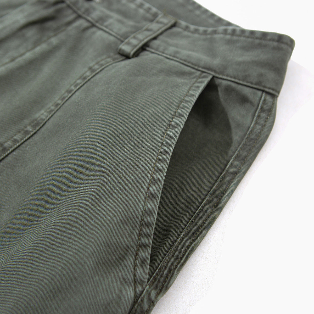 Close-up of gray-green pants showing a slanted side pocket opening and waistband.