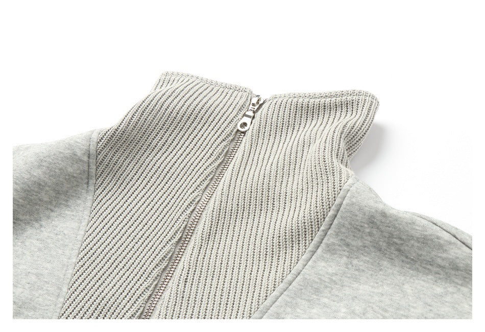 Angled close-up of a light gray jacket's ribbed collar and metal front zipper.