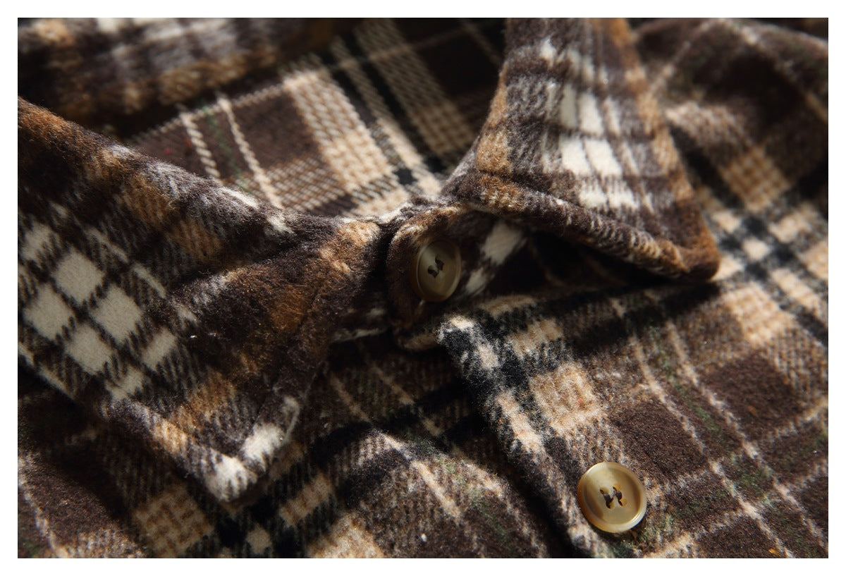 Close-up of a brown plaid shirt with a pointed collar edge and tan buttons.