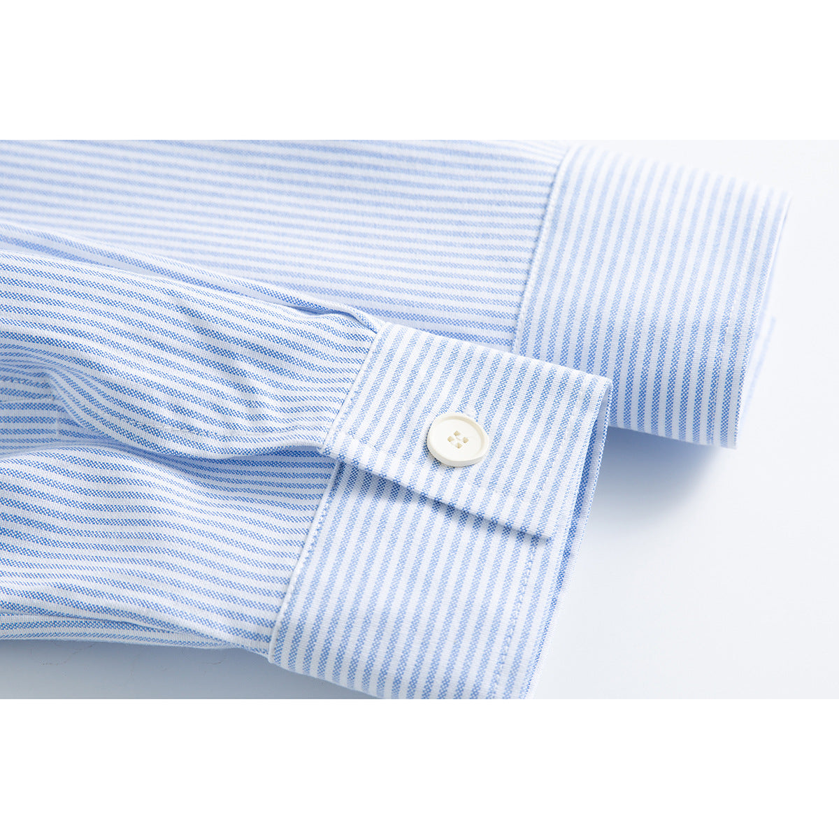 Close-up of a white button on the cuff of a blue-and-white pinstriped shirt.