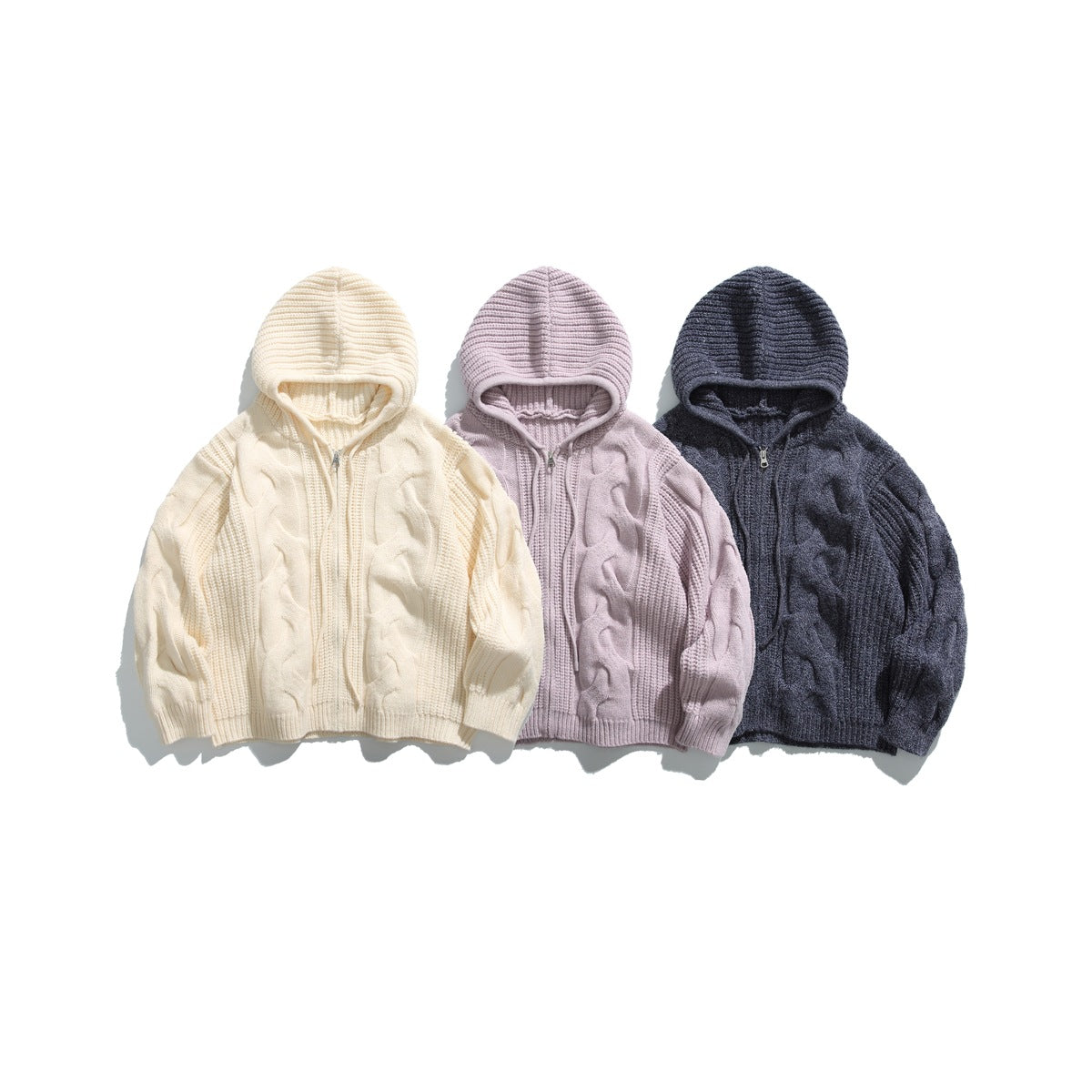 Three front-view cable-knit zip hoodies in ivory, pale mauve, and charcoal.