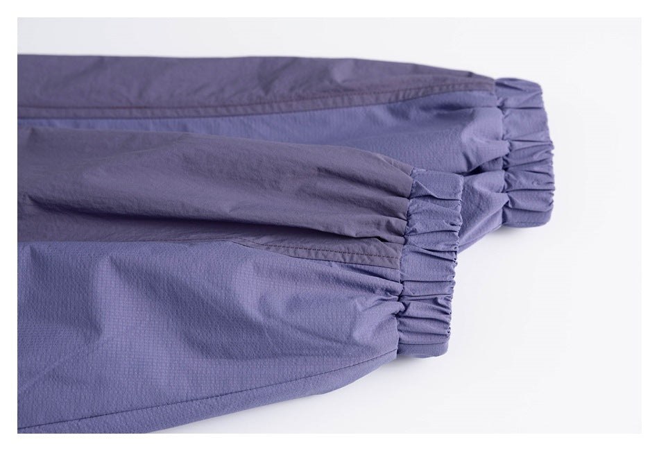 Close-up of two gathered elastic cuffs on a lavender garment with darker paneling.