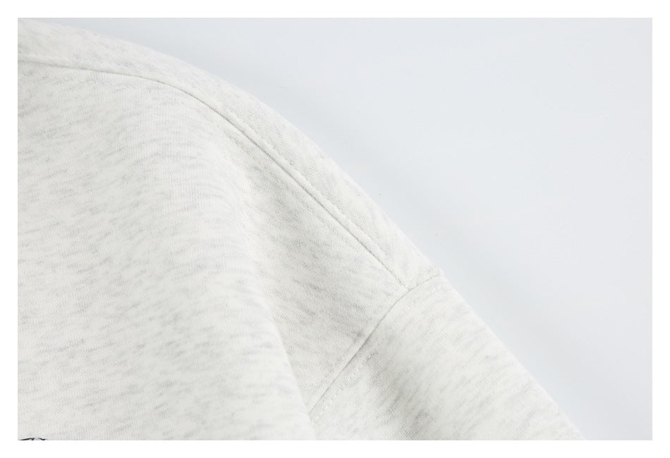 Close-up of the shoulder seam and sleeve on a light gray marled garment.