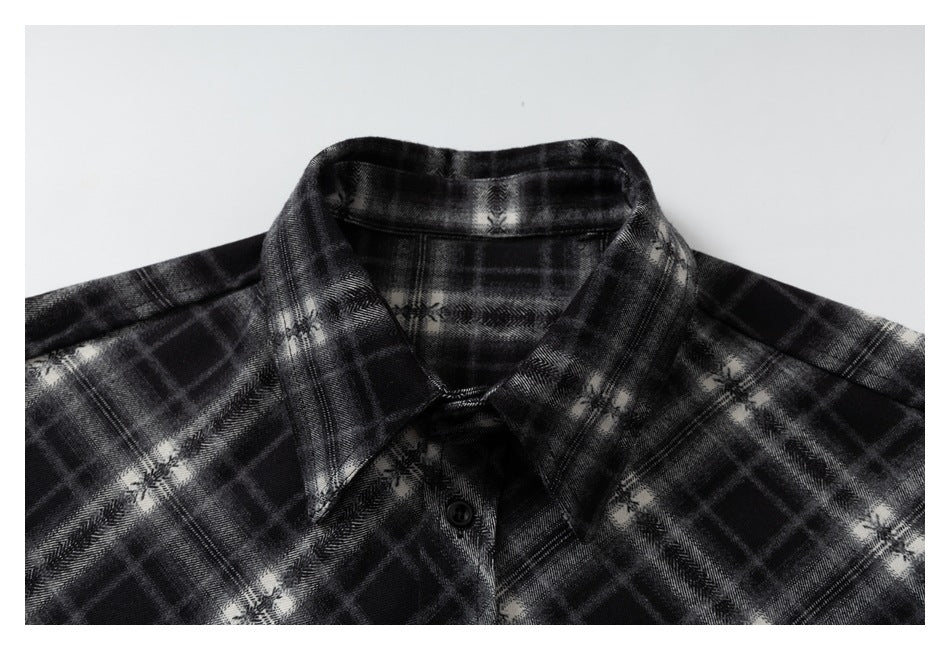 Close-up of the black and gray plaid shirt collar, neckline, and top button.