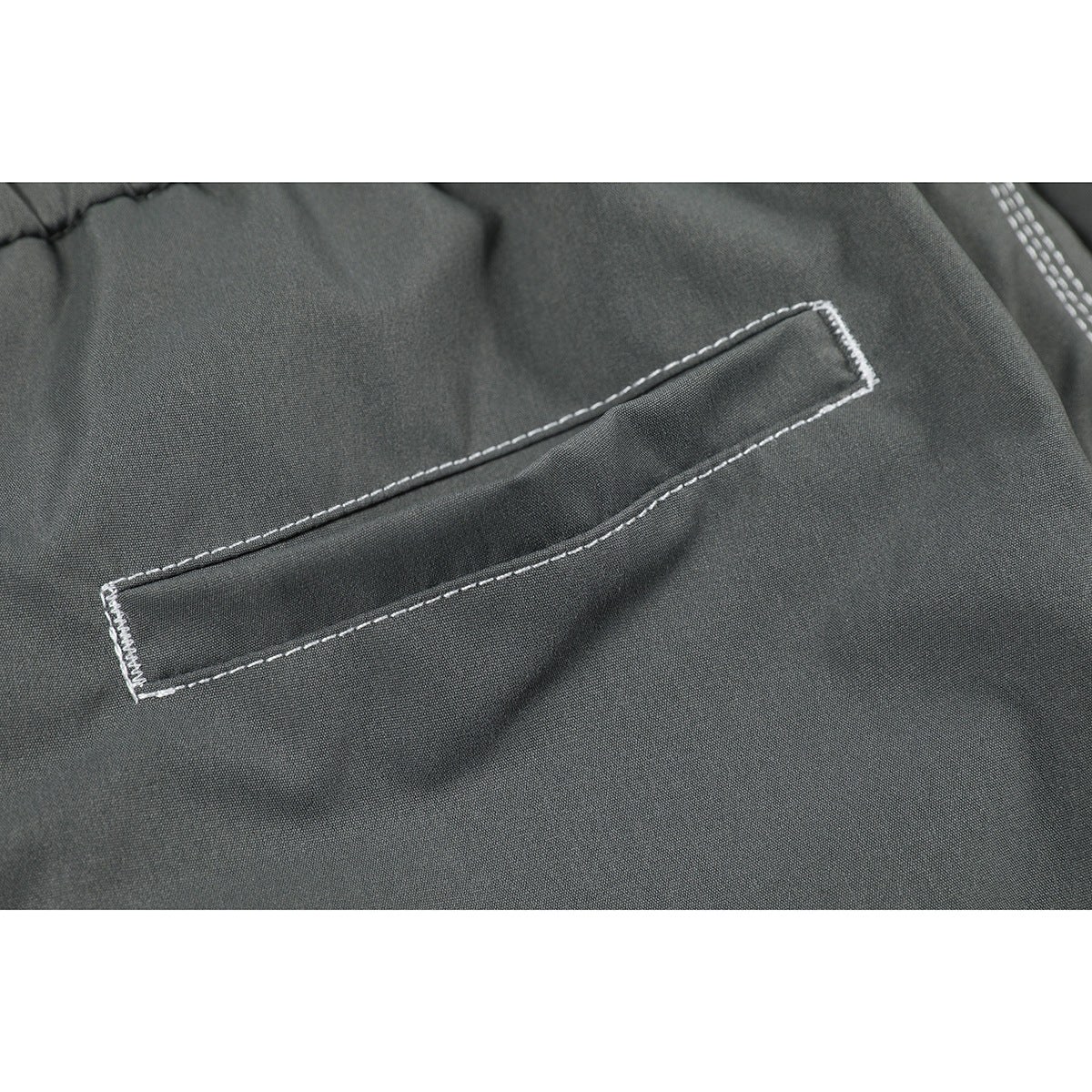 Close-up of a narrow pocket with white stitching on charcoal gray pants.