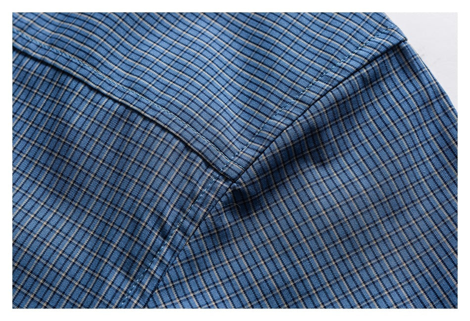Close-up of a blue plaid shirt shoulder seam and folded collar edge.