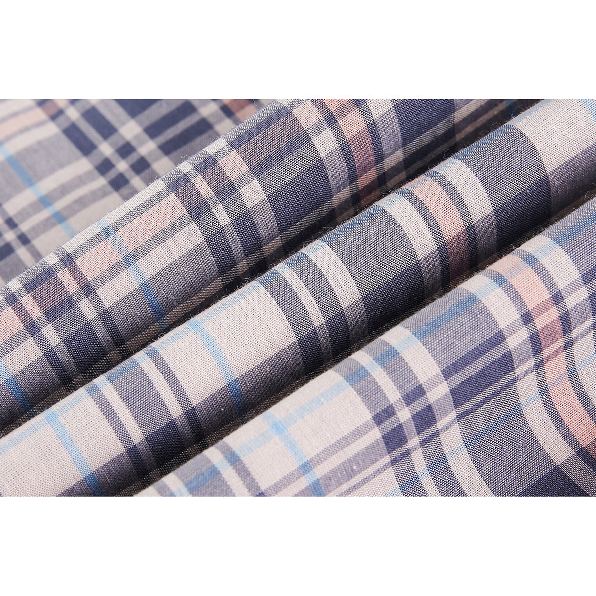 Close-up of pale plaid fabric with navy, light blue, and muted pink stripes, folded into ridges.