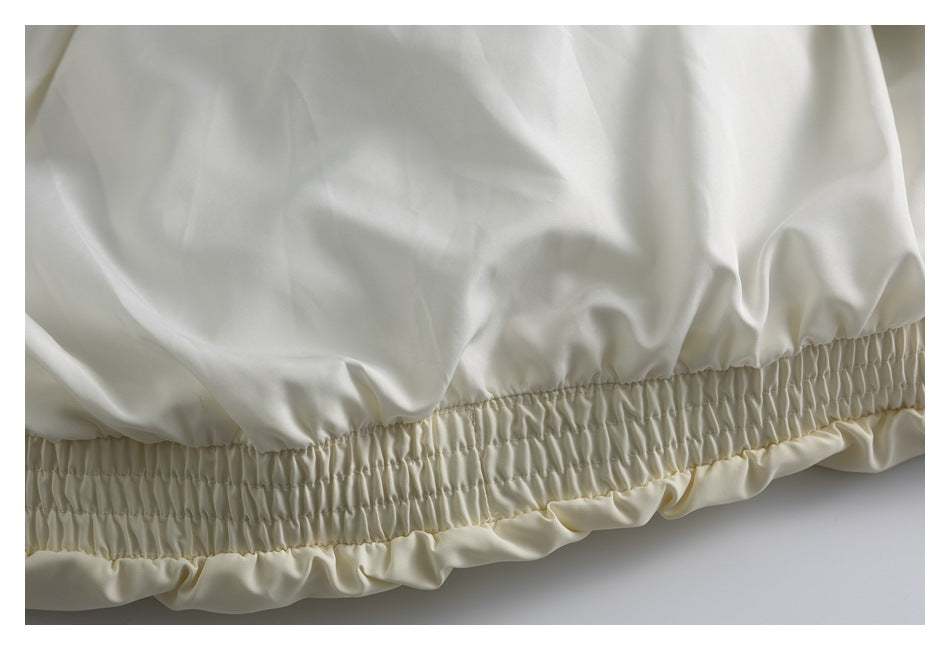 Close-up of a gathered elastic waistband and ruffled edge on pale cream fabric.